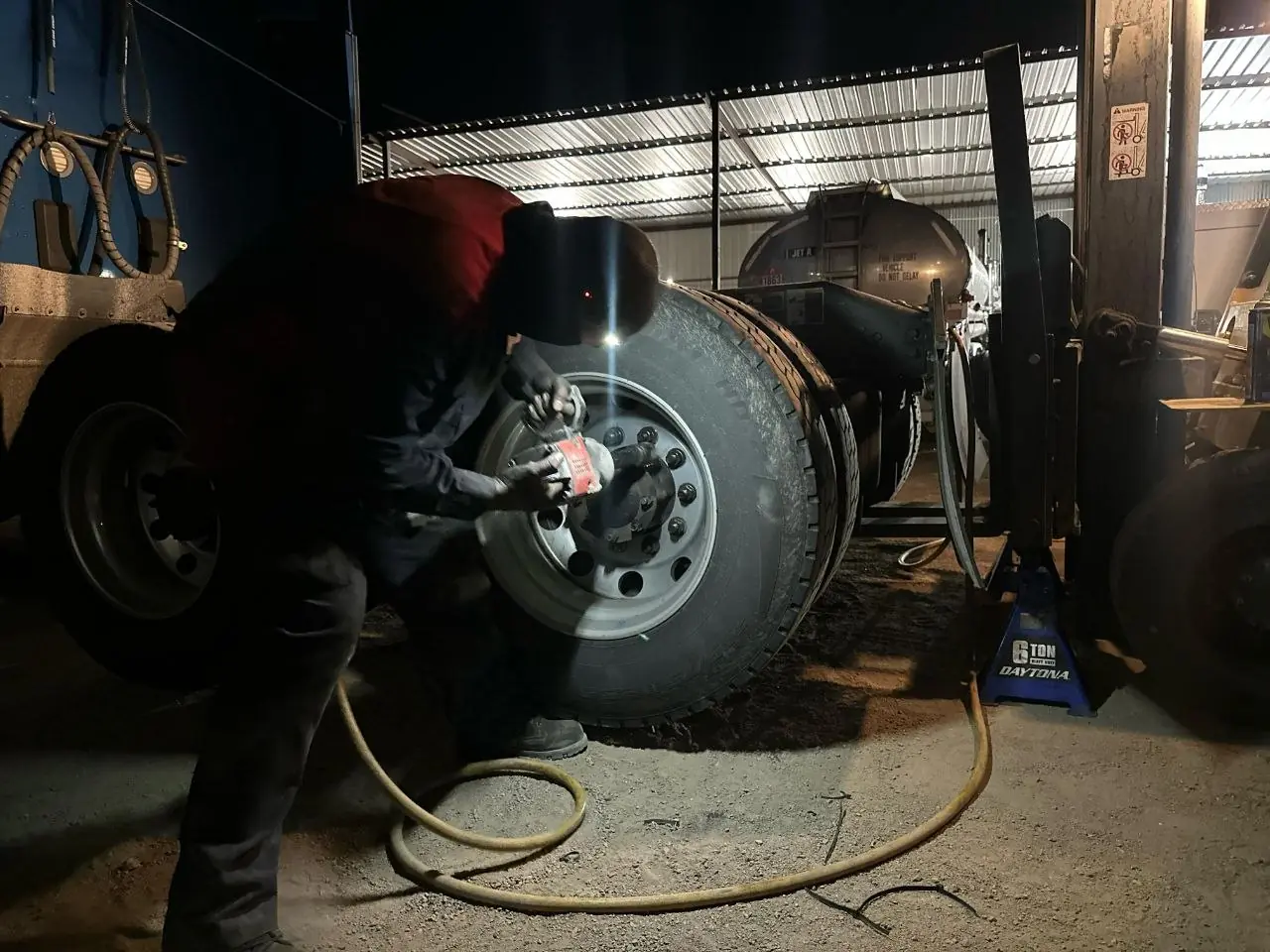 Mechanic removing a truck wheel at night with an impact wrench